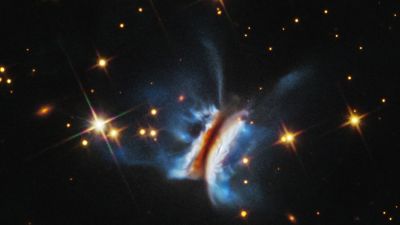 Hubble Space Telescope image of Dracula's Chivito (IRAS 23077+6707), the largest chaotic protoplanetary disk ever observed, with bright wisps of dust extending above and below an edge-on dark dusty disk.