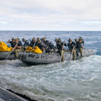 U.S. Navy divers prepare to deploy in small boats from the well deck of USS John P. Murtha to recover...